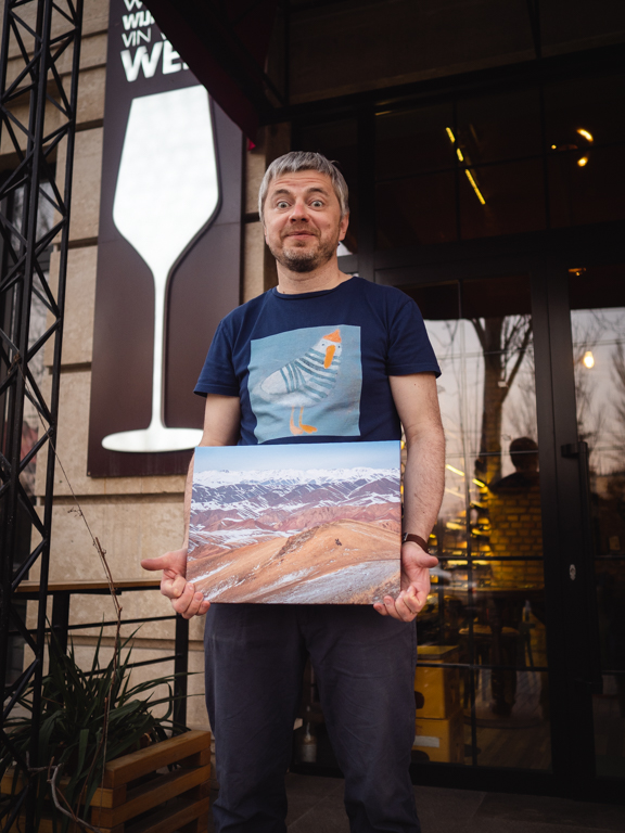 Aleksey con la foto de las montañas de Tian Shan en la vinoteca Vintage. Bishkek, Kirguistán